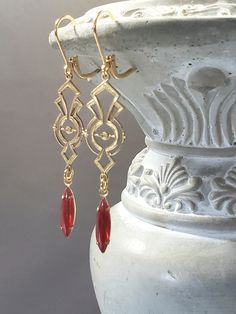 Stunning brass connectors and vintage glass beads (circa 1950s) are featured in these Egyptian Revival inspired earrings. The Czech glass beads are reminiscent of natural carnelian gemstones used in ancient Egyptian jewelry. Egyptian motifs were very popular in 1920s jewelry designs as a result of the discovery of King Tutankhamen's tomb in 1922. The earrings measure 2 1/4 inches long and hang from gold plated lever back ear wires. An elegant lightweight pair of Art Deco style earrings with 1920 Gold Elegant Jewelry, 1920 Earrings, 1920s Accessories Jewelry, Art Deco Style Fashion, 1950 Jewelry, Egyptian Jewelry Ancient, Bobbed Haircuts, Zelda Jewelry, Art Deco Jewelry 1920s