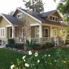 a house with white flowers in front of it and green grass on the side yard