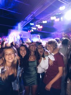 a group of young people standing next to each other at a party with bright lights