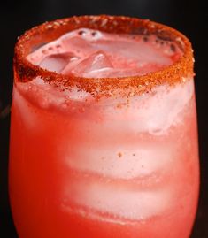 a close up of a drink in a glass with ice and garnish on the rim