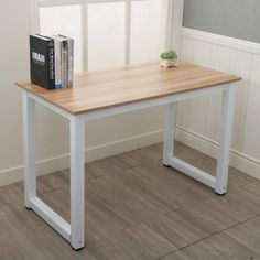 a wooden table with white legs and a book on it next to a window sill