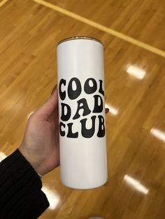 a person holding up a white can with the words cool dad club on it