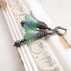 These handmade earrings feature lucite flowers, finely detailed antiqued brass floral details, and Austrian crystal pearls in a dark iridescent purple and green finish. I gave the flowers a translucent, subtly iridescent finish to coordinate with the pearls.  Dimensions and details: - From the top of the lever-back ear wires to the bottom of the dangles, they measure approximately 2.5 inches (64 mm) - Flowers are hand-colored, lightweight lucite. I formulated the color in-house, specifically to Turquoise Flower Earrings, Lucite Flower Earrings, Teal Earrings, Iridescent Green, Vintage Style Earrings, Diy Jewelry Inspiration, Hand Painted Jewelry, Handmade Wire Jewelry, Unique Gifts For Her