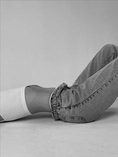 a woman sitting on the floor with her legs crossed and wearing jeans, socks and heels