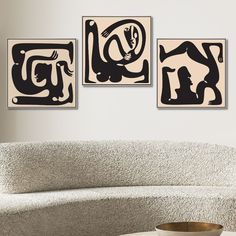 three black and white paintings hanging on the wall above a couch in a living room