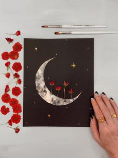 a woman's hand holding onto a card with flowers and a crescent moon on it