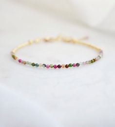 "Spice up your wrist game with our beaded Tourmaline bracelet featuring a vibrant spectrum of colors. From pretty pink to bold black, we've got you covered with a range of natural, faceted tourmaline crystals encircled by 24k gold or sterling silver glass beads. Tourmaline Meaning: Tourmaline is believed to promote inspiration and happiness, reduce fear, and build self-confidence. It is also a birthstone for October. The clasp is sterling silver or 14k gold filled. Gemstone: Natural Tourmaline S Multicolor Beaded Tourmaline Jewelry, Multicolor Tourmaline Beaded Jewelry, Adjustable Spiritual Tourmaline Beaded Bracelets, Adjustable Tourmaline Beaded Bracelets With Gemstone Beads, Adjustable Multicolor Gemstone Beaded Bracelets, Beaded Tourmaline Bracelets, Beaded Tourmaline Bracelets With Round Beads, Beaded Tourmaline Bracelets As A Gift, Spiritual Multicolor Tourmaline Beaded Bracelets