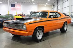 an orange car parked in a garage next to other cars