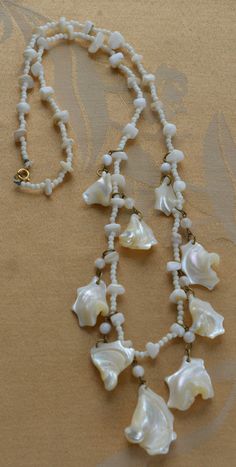 "Pretty vintage white mother of pearl shell beaded necklace is fun and funky. It is long and measures 27\" in length. The necklace is in very good vintage condition and has a spring ring clasp." White Beaded Shell Pearl Necklace, White Shell Necklace For Jewelry Making, White Single Strand Mother Of Pearl Beaded Necklaces, White Single Strand Mother Of Pearl Beaded Necklace, Adjustable White Mother Of Pearl Necklace, Vintage Shell-shaped Beaded Necklaces, Vintage Beaded Shell Necklace With Round Beads, Vintage Beaded Shell Necklace, Vintage Beaded Shell Necklaces