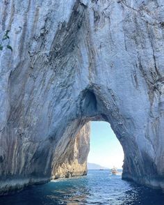 a boat is in the water near a large white rock formation that has been carved into it's sides