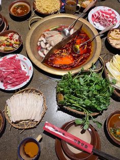 a table topped with lots of different types of food and bowls filled with meats