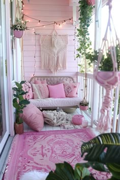 a porch with pink and white decor on the walls, potted plants and pillows