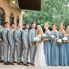 a group of people standing next to each other in front of a brick building with trees