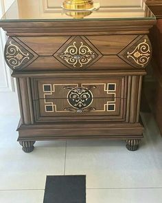 an ornate wooden cabinet with gold trimmings on the front and sides, along with a black rug