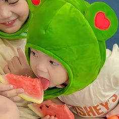 two children in frog costumes eating watermelon