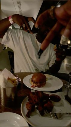 a man cutting into a burger on top of a white plate next to other plates