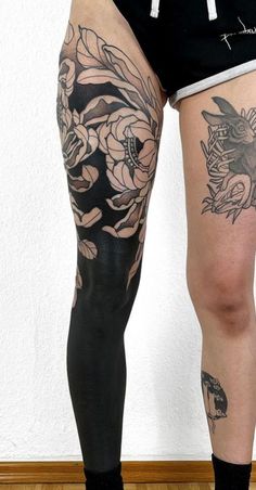 a woman's legs with tattoos on them and flowers in the bottom part of her leg