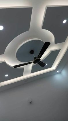 a ceiling fan mounted to the ceiling in a room with white walls and lights on it