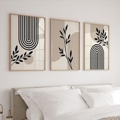 two black and white paintings hanging on the wall above a bed