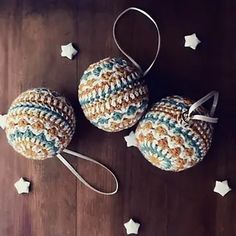 three crocheted ornaments are sitting on a wooden surface with stars around them and one is hanging from a string