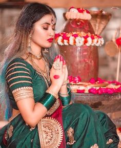 a woman in a green and red sari sitting next to a cake with flowers on it