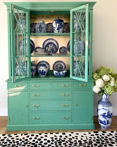 a green china cabinet with blue and white plates on it