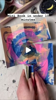 someone is painting on paper with paint and glue in front of the video about how to make an art project