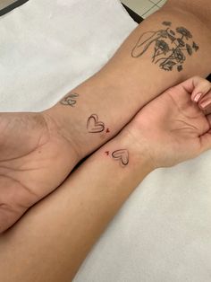 two people holding hands with tattoos on their arms and legs, both showing the same heart