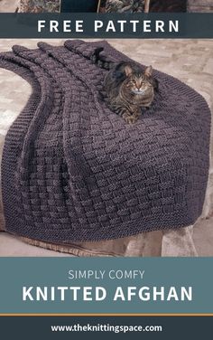 a knitted bag sitting on top of a bed with a cat in the middle