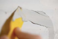 a person holding a piece of paper in front of a wall with peeling paint on it