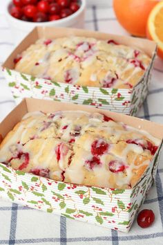 two boxes filled with cake sitting on top of a table next to oranges and cherries