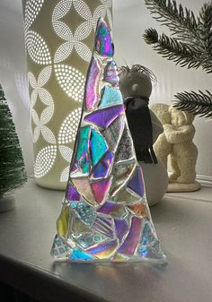 a glass christmas tree sitting on top of a table next to a potted plant