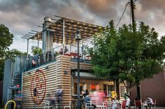 an artist's rendering of a building with people sitting at tables outside