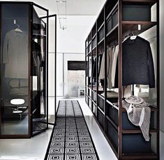 a walk in closet with clothes on shelves