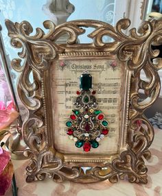 an ornate frame with a christmas tree brooch in it's center surrounded by sheet music