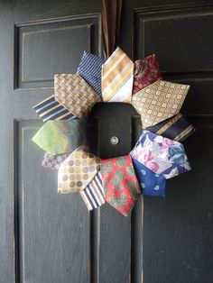 a wreath made out of ties hanging on the front door's black painted doors