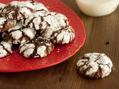 chocolate crinkle cookies are on a red plate next to a glass of milk