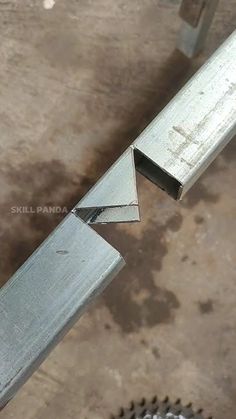 a pair of metal nails sitting on top of a piece of wood