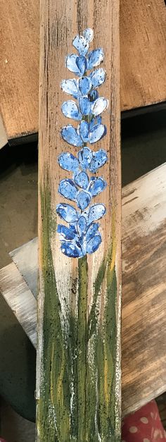 a wooden board with blue flowers painted on the side and green grass growing out of it