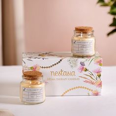 two jars of honey sitting on top of a table next to a flowered box