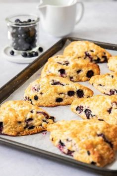 blueberry muffins are on a baking sheet next to a cup of coffee