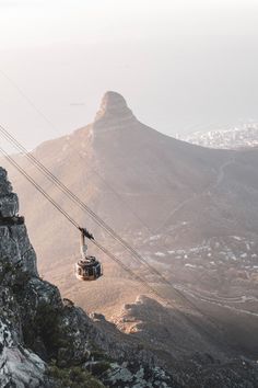 a cable car going up the side of a mountain with mountains in the back ground