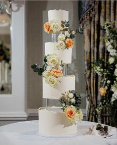 a three tiered wedding cake with flowers on the top and bottom, sitting on a table