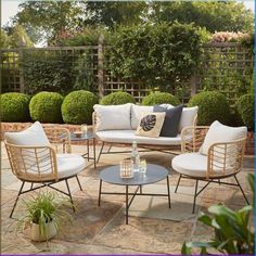 an outdoor seating area with wicker furniture and plants on the ground in front of it