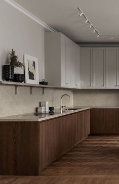 an empty kitchen with wooden floors and white cupboards on the wall above the sink