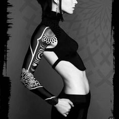 a woman with tattoos on her arms and chest posing for a photo in black and white