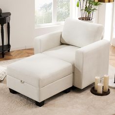 a white chair and ottoman in a living room with a potted plant on the floor