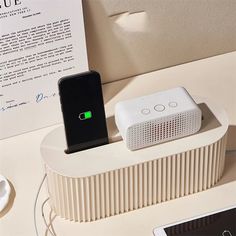 an electronic device charging on top of a white table next to a cell phone and charger