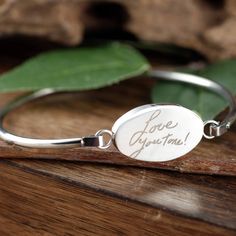 a close up of a bracelet on a wooden surface with a leaf in the background