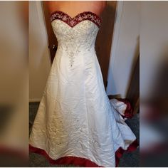 a white wedding dress with red trim on it